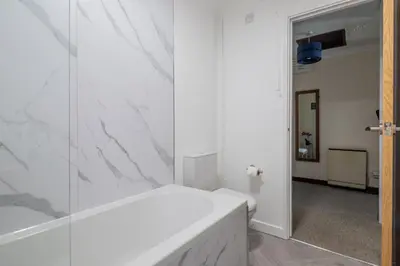 a bathroom with white marble walls and a shower at 1Bed Central Apt With Parking in Chesterton