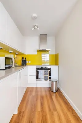 a kitchen with white cabinets and a wooden floor at Chic escape in Cambridge