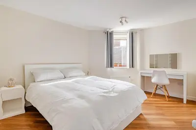a white bedroom with a white bed and a chair at Chic escape in Cambridge