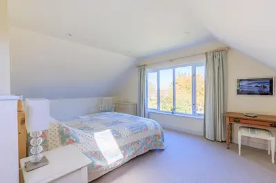 a bedroom with a bed and a large window at Lower Marsh Cottage in Brightlingsea