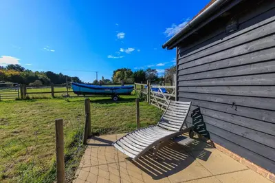 a bench sitting on a sidewalk next to a building at Lower Marsh Cottage in Brightlingsea