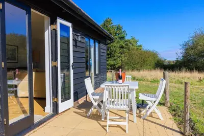 a table and chairs on the porch of a cabin at Lower Marsh Cottage in Brightlingsea