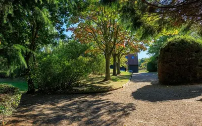 a path with trees and a building in the distance at Lower Marsh Cottage in Brightlingsea