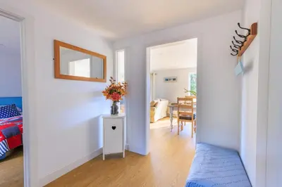 a room with a bed and a table with a vase of flowers at Lower Marsh Cottage in Brightlingsea