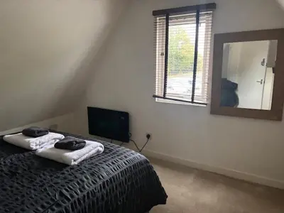 a bedroom with a bed with a mirror and a television at 2 Willow Cottage in Takeley