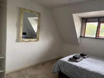 a bedroom with a mirror on the wall and a bed at 2 Willow Cottage in Takeley