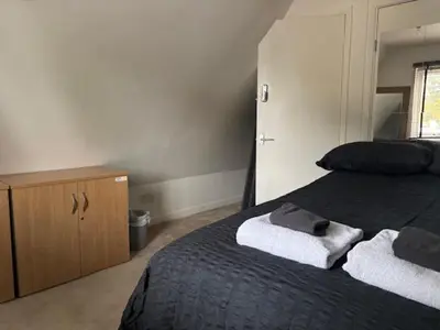a bedroom with a black bed and a wooden cabinet at 2 Willow Cottage in Takeley