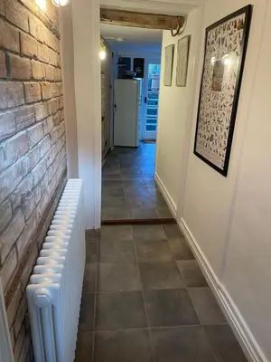 a hallway with a brick wall and a white radiator at The Old Scullery in Bungay