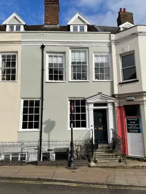 a white house with a red door on a street at The Old Scullery in Bungay