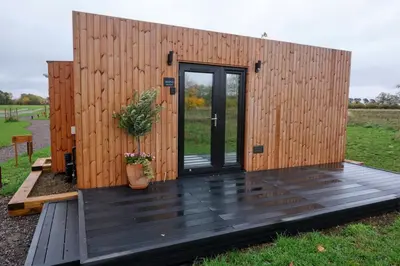 a wooden building with a door on a deck at The Granary Estates