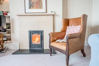 a chair in a living room with a fireplace at 11b Market Cross Place, Aldeburgh in Aldeburgh