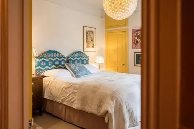 a bedroom with a bed with a blue head board at 11b Market Cross Place, Aldeburgh in Aldeburgh