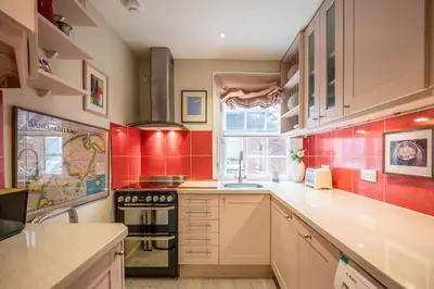 a kitchen with red tiled walls and white cabinets at 11b Market Cross Place, Aldeburgh in Aldeburgh