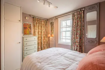 a bedroom with a bed and a dresser and a window at 11b Market Cross Place, Aldeburgh in Aldeburgh