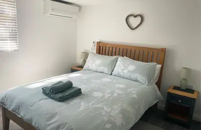 a bedroom with a bed with two green towels on it at Woodstock Park The Tawny Lodge in Wereham