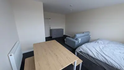 a bedroom with a bed and a table and a chair at Harlech House Flats in Clacton-on-Sea