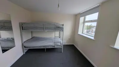 a room with three bunk beds and a window at Harlech House Flats in Clacton-on-Sea