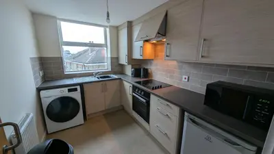 a kitchen with a washer and a sink and a dishwasher at Harlech House Flats in Clacton-on-Sea