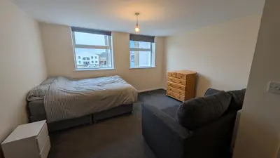 a small bedroom with a bed and a couch at Harlech House Flats in Clacton-on-Sea