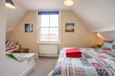 a attic bedroom with a bed and a window at Orlando, Aldeburgh in Aldeburgh