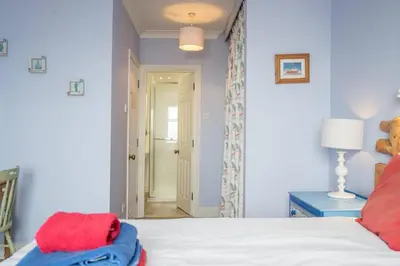 a bedroom with blue walls and a bed with red pillows at Orlando, Aldeburgh in Aldeburgh