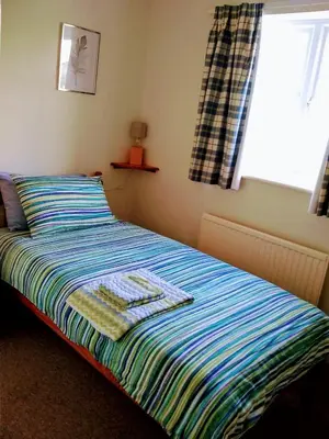 a bed with a striped blanket and a window at Bungalow in Cambridge- 3 bedrooms in CBG
