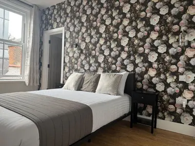 a bedroom with a bed with a floral wall at Sarah Hotel in Harwich