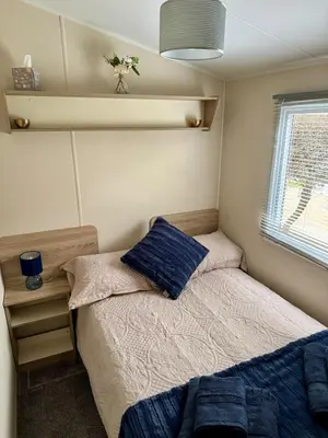 a small bedroom with a bed and a window at Cosy Little Home By The Sea in West Mersea