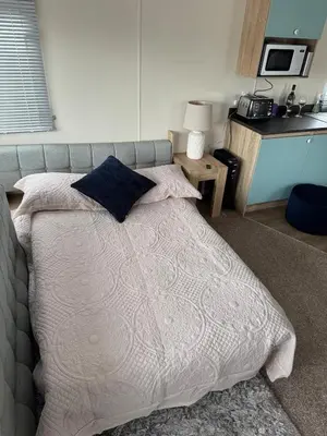 a bed with a white comforter and a blue pillow at Cosy Little Home By The Sea in West Mersea
