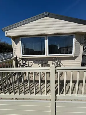 a house with a deck with a table on it at Cosy Little Home By The Sea in West Mersea
