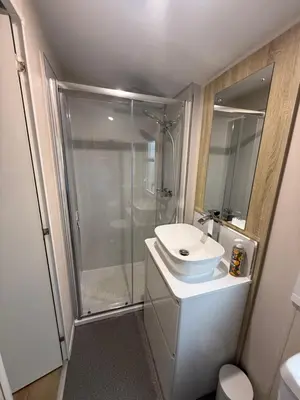 a white bathroom with a shower and a sink at Cosy Little Home By The Sea in West Mersea