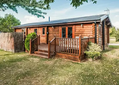 a log cabin with a wooden deck at Laxfield Lodges in Laxfield