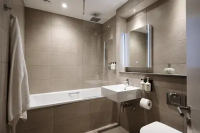 a bathroom with a sink and a mirror and a toilet at The Hobson Cambridge by Adina in Cambridge