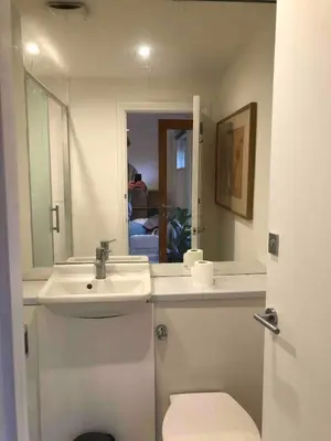 a white bathroom with a sink and a toilet at Self-contained studio with patio in Ware