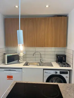 a kitchen with a sink and a washing machine at Self-contained studio with patio in Ware