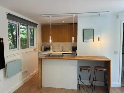 a kitchen with a counter and two bar stools at Self-contained studio with patio in Ware