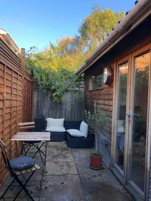 a patio with a couch and a table and a fence at Self-contained studio with patio in Ware