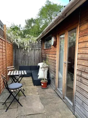 a patio with a bench and a table and chairs at Self-contained studio with patio in Ware