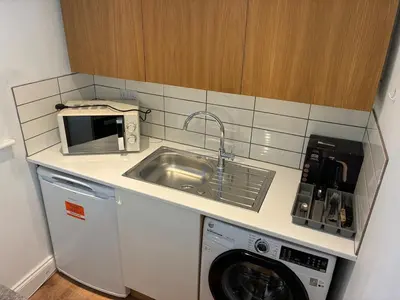 a kitchen with a sink and a washing machine at Self-contained studio with patio in Ware
