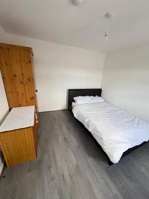 a bedroom with a white bed and a wooden cabinet at Bronze house in Friern Barnet