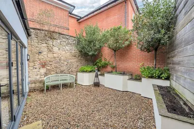 a garden with a bench and trees in a brick wall at GROUND floor apartment no steps 119 Northgate St luxury 2 bedroom apartment close to the town centre with paid parking close by in Bury Saint Edmunds