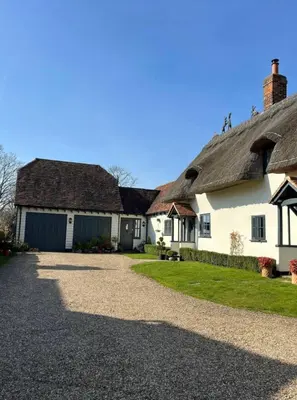 a house with a thatched roof and a driveway at Sunnyside Cottage in Great Sampford