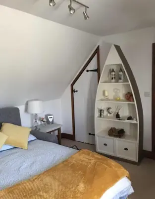 a bedroom with a bed and a book shelf at Sunnyside Cottage in Great Sampford