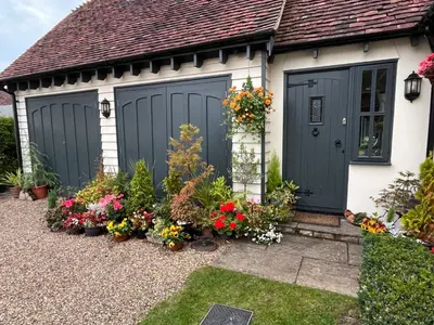 a house with two garage doors and flowers at Sunnyside Cottage in Great Sampford