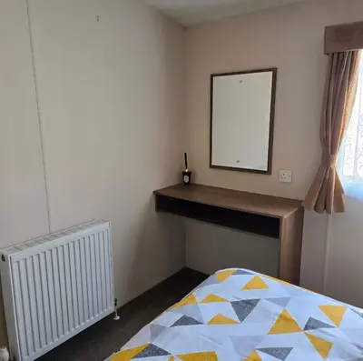 a bedroom with a bed and a mirror on the wall at Coastal Retreats in Great Clacton