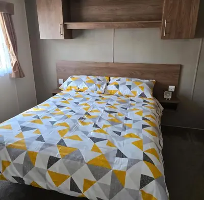 a bed with a colorful quilt on it in a bedroom at Coastal Retreats in Great Clacton