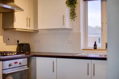 a kitchen with white cabinets and a window at Pass the Keys Stylish and Modern Flat with Free Parking in Cambridge