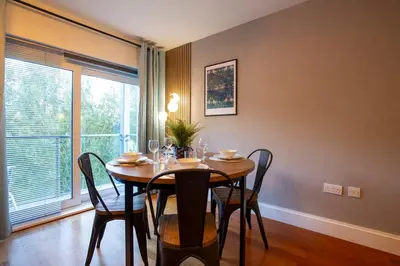 a dining room with a table and chairs and a window at Pass the Keys Stylish Riverside Apartment with Free Parking in Cambridge