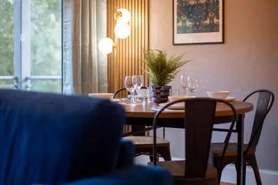 a dining room table with wine glasses and a plant on it at Pass the Keys Stylish Riverside Apartment with Free Parking in Cambridge