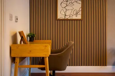 a desk and a chair next to a wall with stripes at Pass the Keys Stylish Riverside Apartment with Free Parking in Cambridge